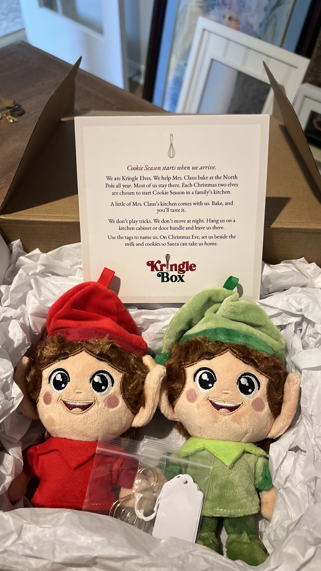 Red and green Kringle Elves in tissue paper with the Kringle Elf story card